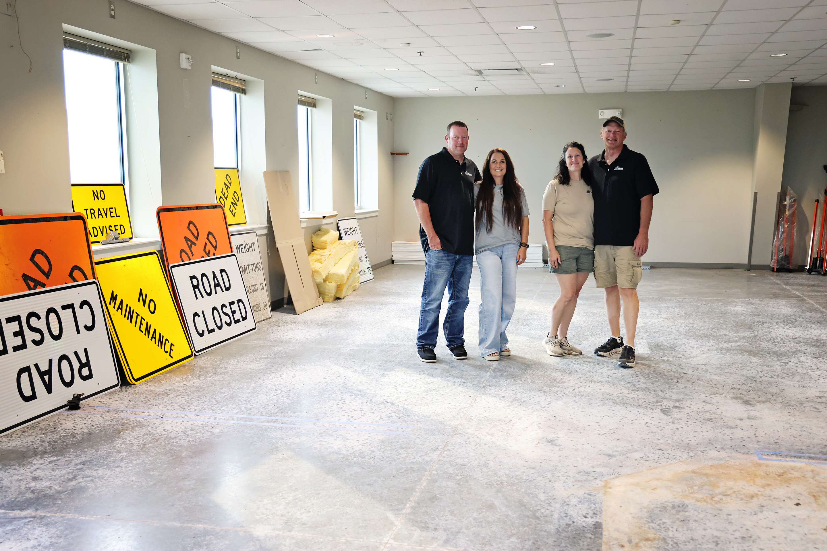 From left, Michael and Jen Feistner and Jennifer and Brian Feistner stand inside the former American Legion building, which the family recently purchased for Feistner Excavation and Gravel. Road closed and no maintenance signs are among the first job materials moved into the building, where work has begun on a large overhead door on the north side for storage access. Construction of office space is planned for this fall. (KRISTI HINE / TRUE DAKOTAN)