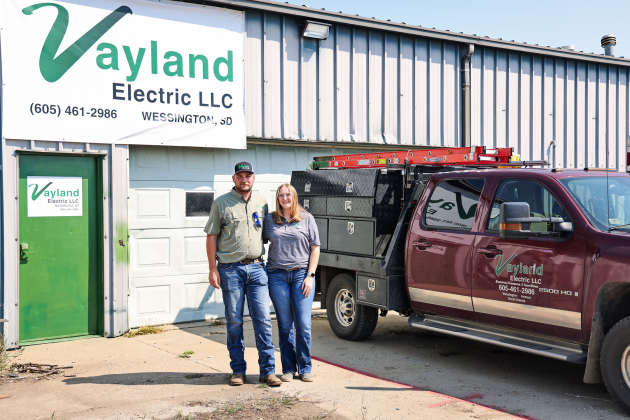 Logan and Josie Schiltz stand outside the Vayland Electric shop near Wessington, where Logan launched his electrical contracting business in January. The shop once housed his grandfather’s Schiltz Manufacturing operation, adding a new chapter to the family property’s entrepreneurial history. (KRISTI HINE / TRUE DAKOTAN)