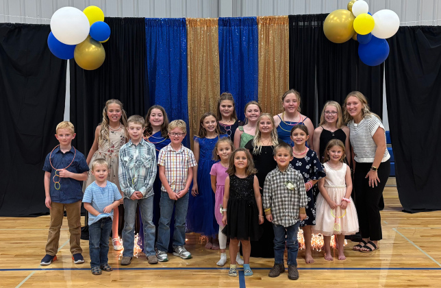 Little Spartans gather with event organizer Kendall Kolousek for a photo during the Little Spartans Homecoming Prom. Kolousek organized the event as her senior project, giving students in grades K-6 a chance to dress up, have fun and make Homecoming memories of their own. (PHOTO COURTESY LIZA KOLOUSEK)