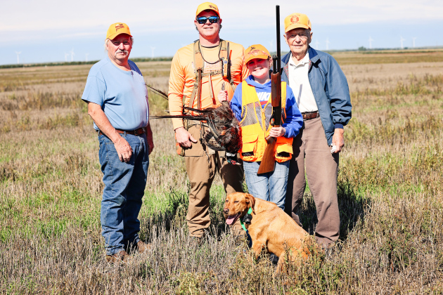Four generations of hunting tradition come together following the Oct. 3 Pheasants Forever Youth Hunt. From left, Steve Winter, Jason Weber, Hadley Weber and Dayle Winter stand in the field with Hadley’s first pheasant. Hunting dog Minnie joins the group in front.