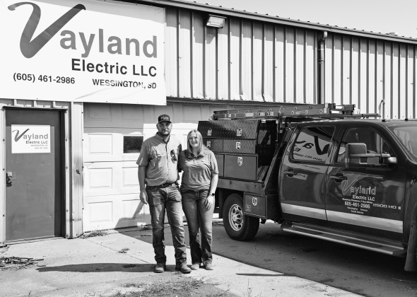 Logan and Josie Schiltz stand outside the Vayland Electric shop near Wessington, where Logan launched his electrical contracting business in January. The shop once housed his grandfather’s Schiltz Manufacturing operation, adding a new chapter to the family property’s entrepreneurial history. (KRISTI HINE / TRUE DAKOTAN)
