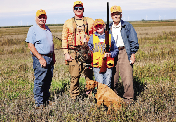 Four generations of hunting tradition come together following the Oct. 3 Pheasants Forever Youth Hunt. From left, Steve Winter, Jason Weber, Hadley Weber and Dayle Winter stand in the field with Hadley’s first pheasant. Hunting dog Minnie joins the group in front.