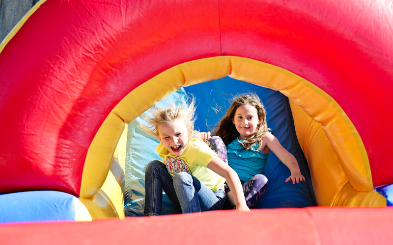 Cara Van Dyke (right) and a friend slide down the bouncy house at the family-friendly event.