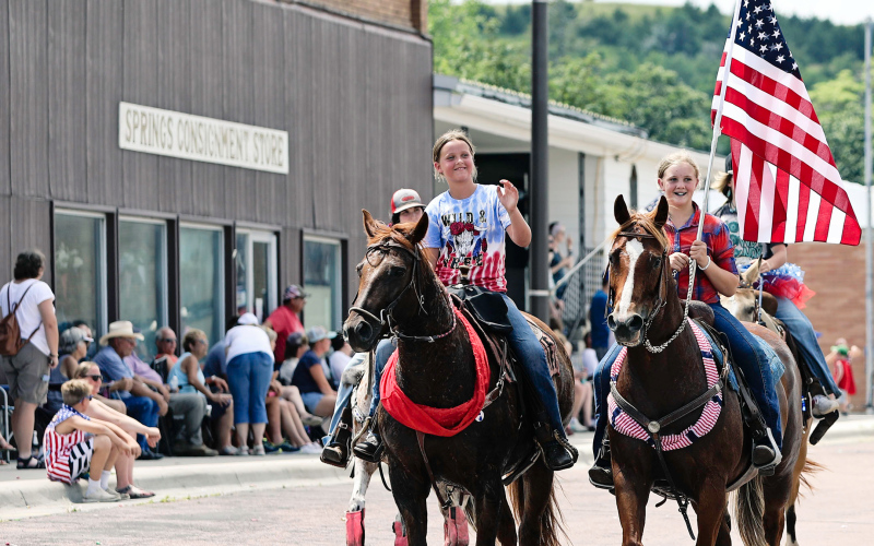 Jerzie Poncelet, Lilliya Meek and Old Glory lead the horse riders in the parade east on Main Street.