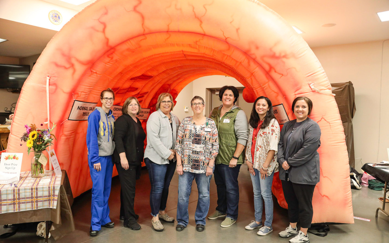 Event organizers from the local health care campus’ Health Education Team are shown in front of the "The Rollin’ Colon" educational exhibit left to right: Katee Olinger, Wendy Bergeleen, Vicki Linke, Ellen Powell, Melissa Mentele, Sarah Knippling and Annie Borgmann.