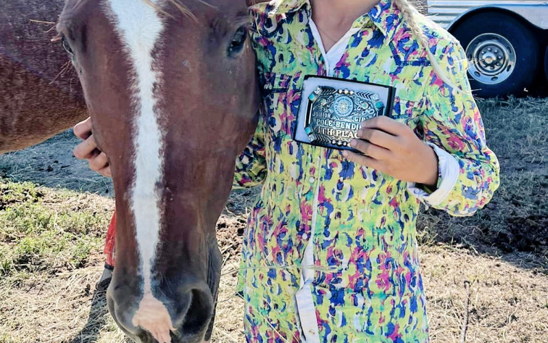 Londyn Mikkelson is pictured displaying the buckle she won for 4th Place Overall in Pole Bending.