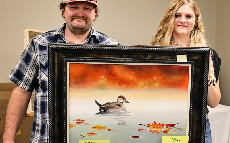 Local artist Kenzee Schafer (right) donated an original painting to be auctioned at the banquet, which brought a whopping $6,100. After a heated back-and-forth between bidders, Blake Messmer claimed the winning bid of the artwork.