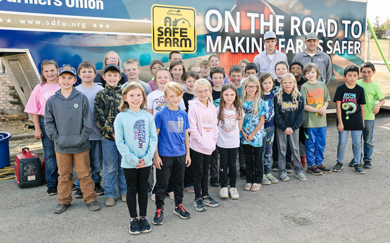 Schimke is pictured with project mentor Rocky Forman of SDFU alongside WSES 3-4 graders in front of the SDFU Farm Safety Trailer.