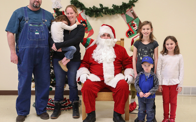 Regulars each year at Santa Saturday, the Van Dyke family posed for a family photo with Kris Kringle. Shown left to right are: Darrick, Jessica (holding a shy Britton), Santa, Devin, Cara and Kase Van Dyke.