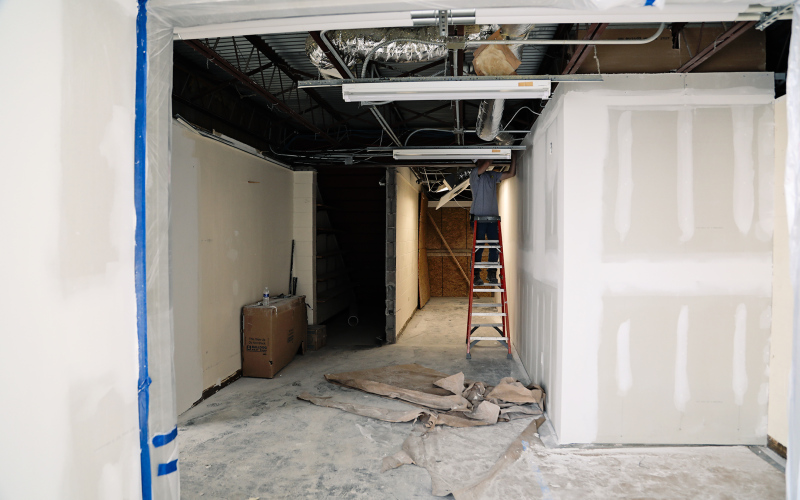 An electrician works in the corridor that connects to the existing gymnasium.