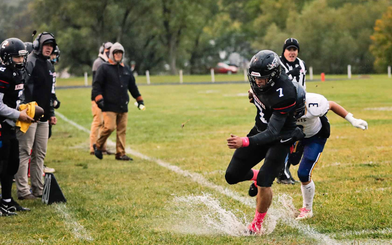 Holden Havlik runs the football out of bounds, evading a tackle but landing ankle deep in a puddle. Soggy field conditions made moving the football a task for both the Blackhawks and Rapid City Christian.