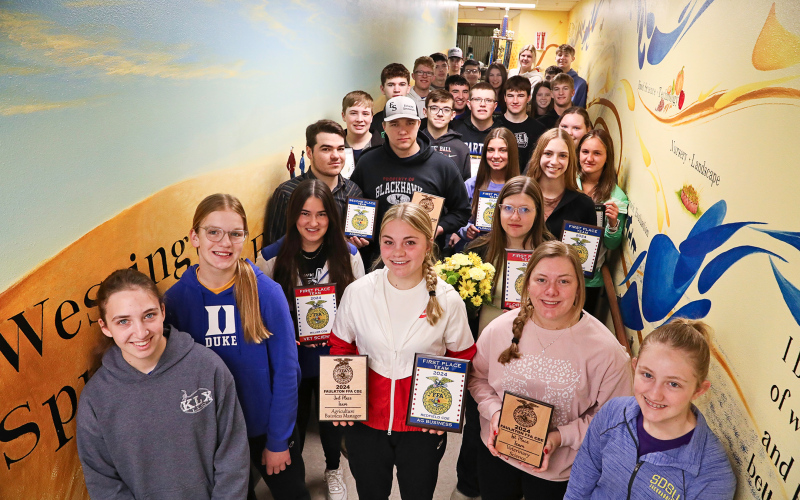 Gathered with their fellow Wessington Springs FFA Chapter members, state-bound students display recent awards they’ve earned at area Career Development Events (CDEs). They are shown in the celebrated mural-lined FFA hallway leading to the vo-ag shop at Wessington Springs High School (WSHS). The mural, painted by WSHS alumna and former FFA member Kenzee Schafer, depicts the rich history of the local chapter’s FFA program.