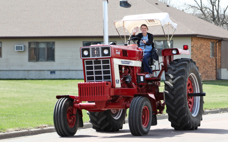 Wessington Springs High School senior Hannah Heezen smiles and waves atop a beautifully restored International during Monday’s 2nd annual tractor parade.