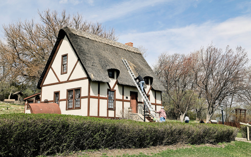 Tom Dean holds the ladder as Joel Boschee makes repairs on the roof of Anne Hathaway Cottage at Shakespeare Garden.