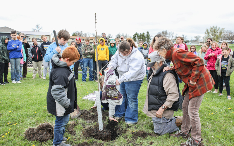 Tom and Kathy Dean, who donated the tree, along with friends and family of Reba Carothers, plant a bur oak at the south end of the playground.