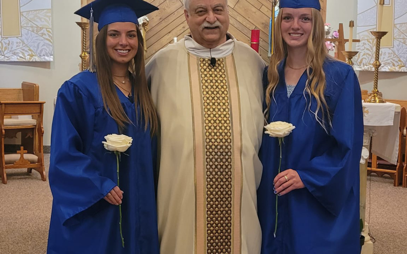 Class of 2024 graduates Alyssa Grohs and Abby Kolousek are shown at St. Joseph Catholic Church with Fr. Terry Weber.