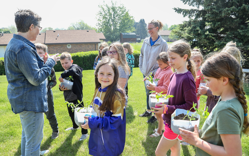 All smiles upon arriving at Shakespeare Garden with her pot of zinnias and second grade classmates, Raven Richardson said she was excited to plant her flowers in their “home for the summer.”
