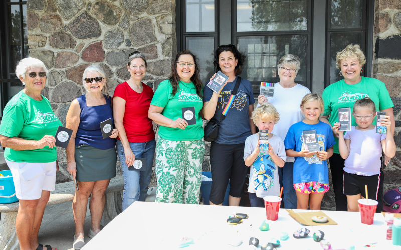 SACOTA board members pause for a photo with door prize winners. Shown left to right, back row are: SACOTA board member Diane Winter, former board member Deb Kogel, SACOTA board members Becky Easter, Mara Meier, Art in the Park attendees Kelly Perry, Cathy Perry and SACOTA board member Carrie Azure. Front row: Axle Kurth, Carlayna Waters and Eleanore Moe.