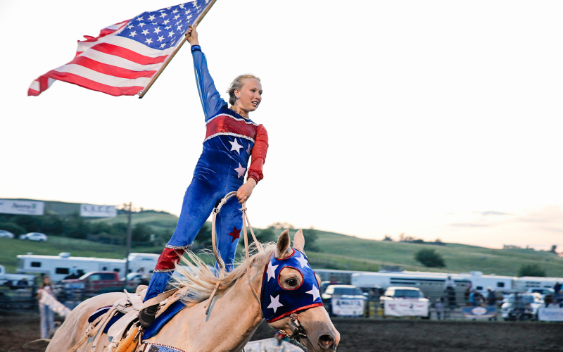 Crazy Cowgirl Trick Rider Candice Aamot proudly displays Old Glory as part of her routine at the Foothills Rodeo Friday evening, July 5.