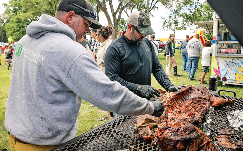 Jason Weber and Jarrod Bultsma shred tender pork off a whole hog that Weber donated and smoked for the event.