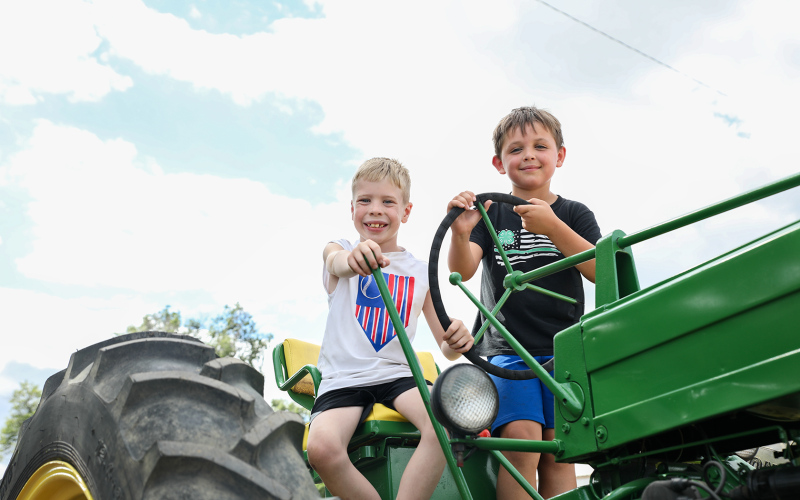 Bosten Jensen and Jesse Arhart smile for a photo atop the Jensen antique tractor entry.