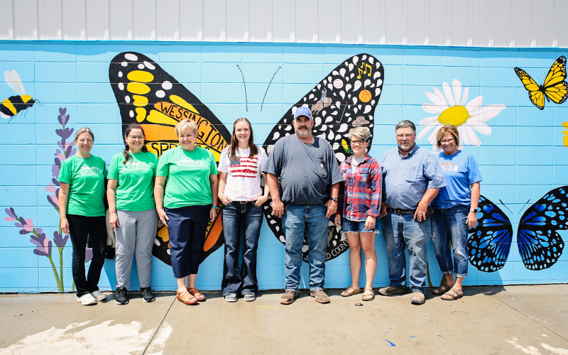 Shown at the July 4 Springs Area Council of the Arts (SACOTA) mural unveiling at the pool house in Wessington Springs are, left to right: SACOTA BOARD MEMBERS Becky Easter, Mara Meier, Carrie Azure, mural artist Ruthe Lindvall, Wessington Springs Mayor Ryan Knipfer, Wessington Springs City Council Members Kari Fagerhaug, Pat Fastnacht and Vicki Harmdierks. KRISTI HINE / TRUE DAKOTAN