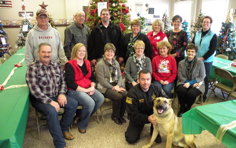 In lieu of a gift exchange, Jerauld County employees chose to make monetary donations toward the care of Ajax, the  Sheriff’s Department K-9 drug dog. shown are, top row, from left: Marilyn Hinrichs, Roger Dwyer, Bonnie Koch, Natalie Wolfskill; fourth row: Cindy Peterson, Connie Ness, Janice Bender; third row: Mette Ness; second row: Deputy Sheriff Shane Mentzer, Sheriff  Jason Weber. Ajax, shown in the front row, appears to enjoy having his picture taken. TRUE DAKOTAN FILE PHOTO
