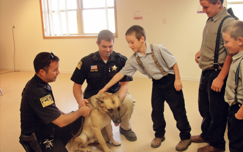 Ajax, Sheriff Jason Weber (center)( and Deputy Shane Mentzer visited the Spring Valley School children. The children got to watch Ajax do some of his work, like finding hidden object, sniffing out illegal drugs and solving problems.  The kids asked questions about Ajax’s training, how they take care of him, and what it is like to work with a police dog.