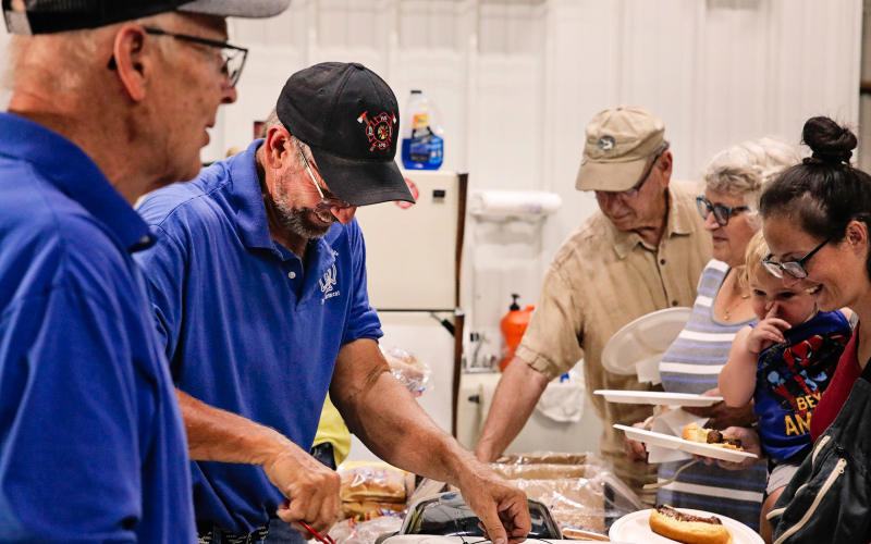 Wessington Springs Volunteer Firemen Mike Mebius and Jerry Van Den Oever laugh with community members as they serve a long line of attendees at the 2024 Firemen’s FunFest.