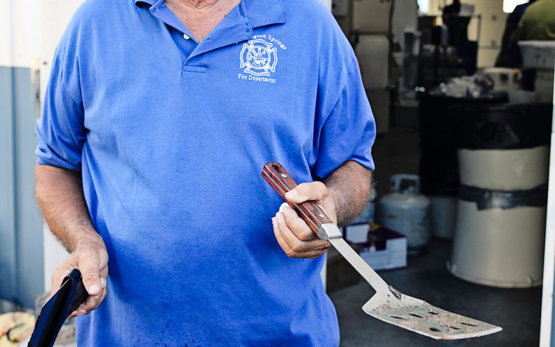 Kim Shultz shares a smile while staying busy on the grill for hours as locals and visitors alike lined up for brats and burgers Friday night.