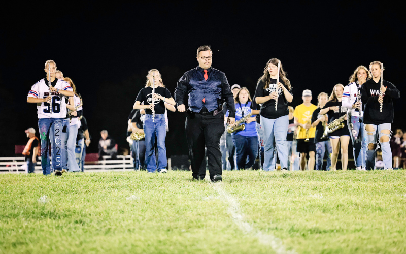 Band instructor Andrew McCormick leads the marching band onto the field last Friday night during halftime.