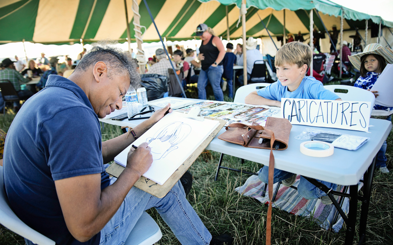 At Friday’s camp, Springs Area Council of the Arts (SACOTA) sponsored caricature artist Hector Curiel to draw portraits of attendees free of charge. Kaddilac Coleman smiles as he sat down for his turn with the artist.