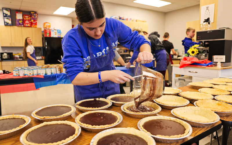 As area families sit down to enjoy their Thanksgiving meal together this Thursday, chances are they’ll be savoring a pie made by Wessington Springs High School (WSHS) students, as part of a longstanding local tradition. Pictured hard at work Tuesday during the annual service-oriented pie baking project, Remie Roduner spoons chocolate filling into pie crusts. KRISTI HINE / TRUE DAKOTAN