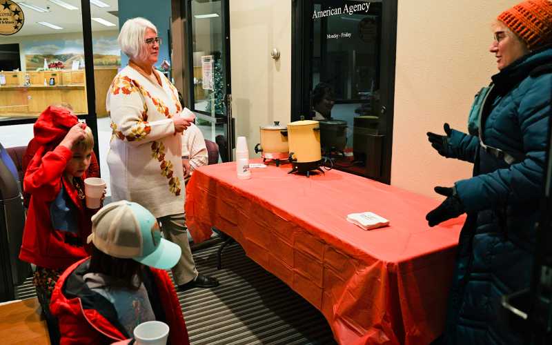 Eileen Thomas visits with American Bank &amp; Trust employee Melanie Schelske as she served up sweet treats and hot cocoa to event goers in the bank’s Main Street entryway.