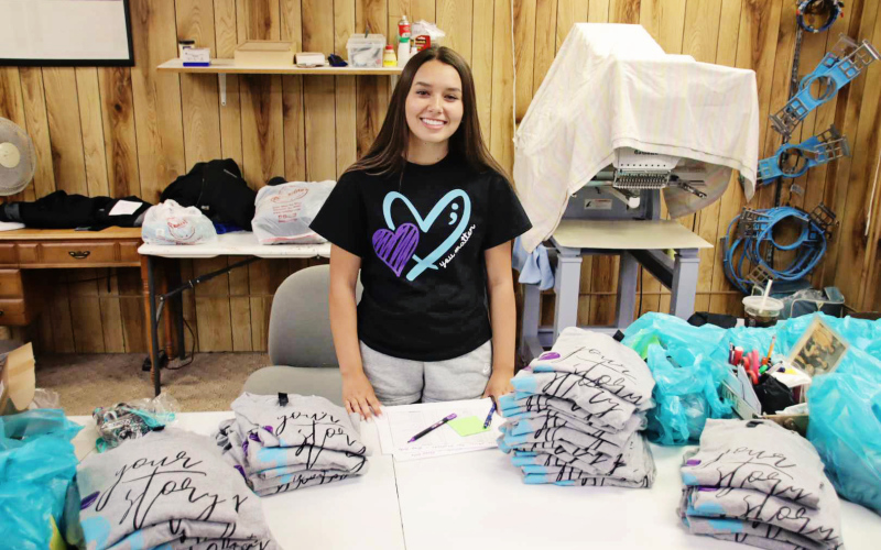 BENJAMIN CHASE / PLAINSMAN Huron High School senior Cadence Kogel sorts through stacks of the t-shirts that she worked with PB Sports to produce for Monday’s Day of Hope in Huron.