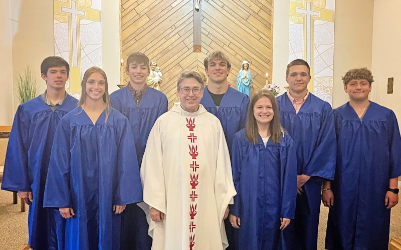 Graduates donned their gowns for a celebration honoring the seniors at St. Joseph Catholic Church. Shown left to right are: Karter Mebius, Bailey Yost, Landen Christensen, Fr. Larry Regynski, Holden Havlik, Kennedy Kolousek, Robert Hine, Will Bruckner.