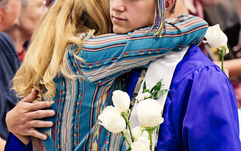 WSHS graduate Robert Hine hugs his mom, Kate Schmidt, during an emotional flower presentation to family and friends.