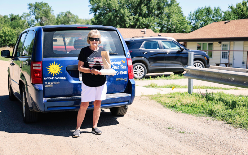 Springs Area Bus driver Joanne Grohs delivers meals from the Senior Citizens Center Nutrition Site to a patron at Hillcrest Heights Apartments in Wessington Springs on Tuesday, July 1, 2025. Last week, the “Meals on Wheels” service provider, Rural Office of Community Services (ROCS), announced that it would no longer be able to provide meal delivery services or church transit via Springs Area Bus unless it receives community financial support. KRISTI HINE / TRUE DAKOTAN