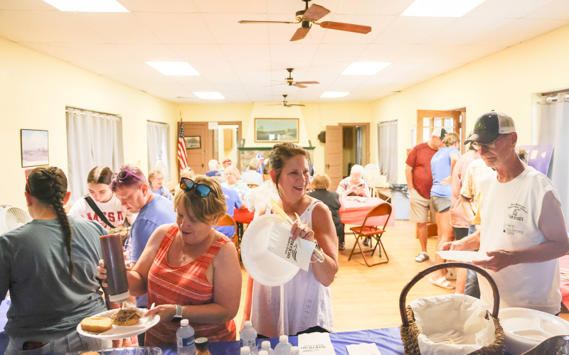 Linda Willman, Teresa and Craig Fonder dish up pulled pork sandwiches accompanied by chips and cookies, served up by Melanie Schelske.