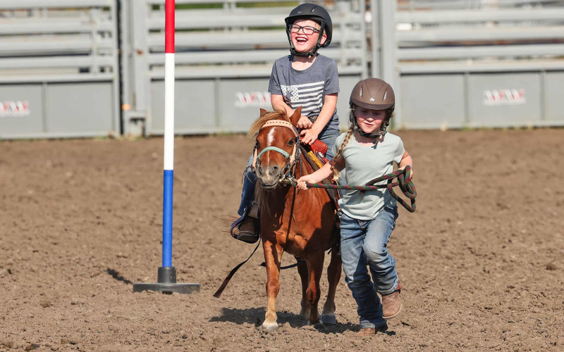 Kimber Shryock leads brother Colt through a pattern during the August 11, 2025 Foothills PlayDays. The youth, in Wessington Springs visiting grandparents Craig and Kelli, were among hundreds of children from across the region to participate in the event. KRISTI HINE / TRUE DAKOTAN
