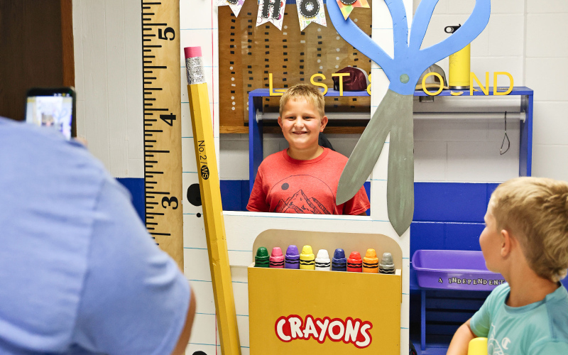 Chelsea Cashman snaps a cell phone photo of son Hayes as his brother Harvey looks on during Back-to-School Night.