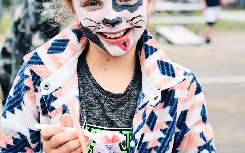 Mary Tanke enjoys a treat from the “Sno Shack” while donning a puppy-painted face.