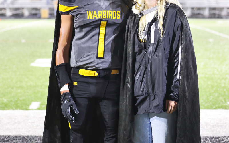 Homecoming King Caleb Richmond and Queen Kendal Uttecht smile through the raindrops during halftime at Friday’s homecoming game in Huron.
