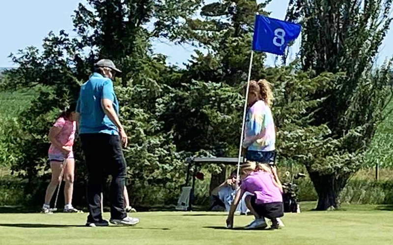 Clinic organizer Gloria Vavra offers guidance on the putting green, helping participants develop skills and respect for the game during the summer youth golf clinics at Springs Country Club.
