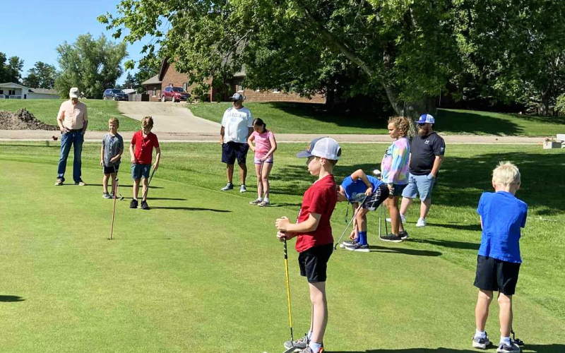 Young golfers focus on their form during the youth golf clinics at Springs Country Club, where volunteers helped participants practice putting, chipping, and fairway play while learning golf etiquette and sportsmanship.
