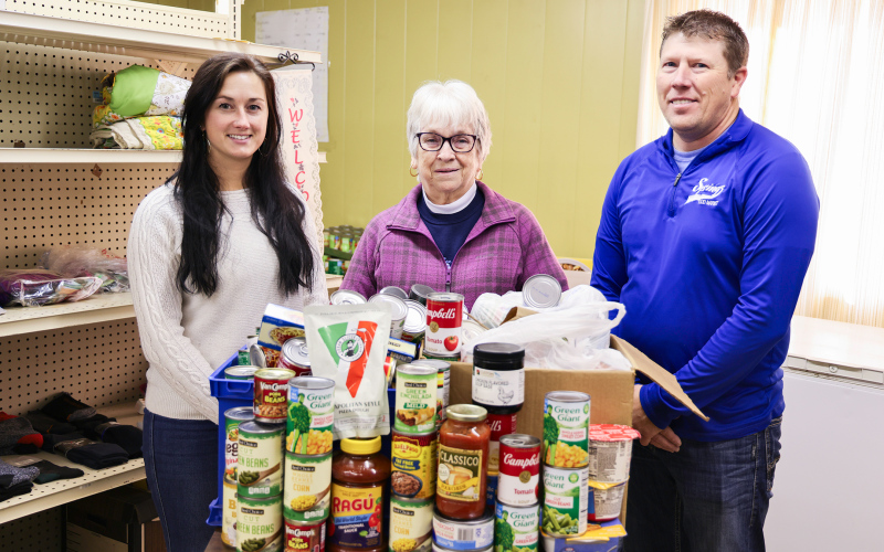 Bethany Schimke, Marcella Andersen, and Ryan Jensen stand with this year’s Caring Rose Week donation at the Jerauld County Food Pantry. The 2025 campaign brought in hundreds of non-perishable items along with a matching contribution from Springs Food Market. (KRISTI HINE / TRUE DAKOTAN)