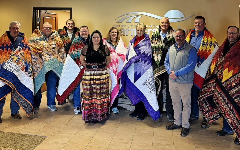 Farmers Union Board members are gifted Star Quilts by Team Buche Cares for their donation to the non-profit focused on feeding the hungry in rural and tribal communities. Left to right: David Reis, Chad Johnson, Jeff Kippley, Doug Sombke, Anna Halverson, Pass Creek Tribal Council Representative of the Oglala Sioux Tribe; Gail Temple, Karla Hofhenke, Larry Birgen, RF Buche, Team Buche Cares; Scott Kolousek and Oren Lesmeister. (COURTESY OF TEAM BUCHE CARES)
