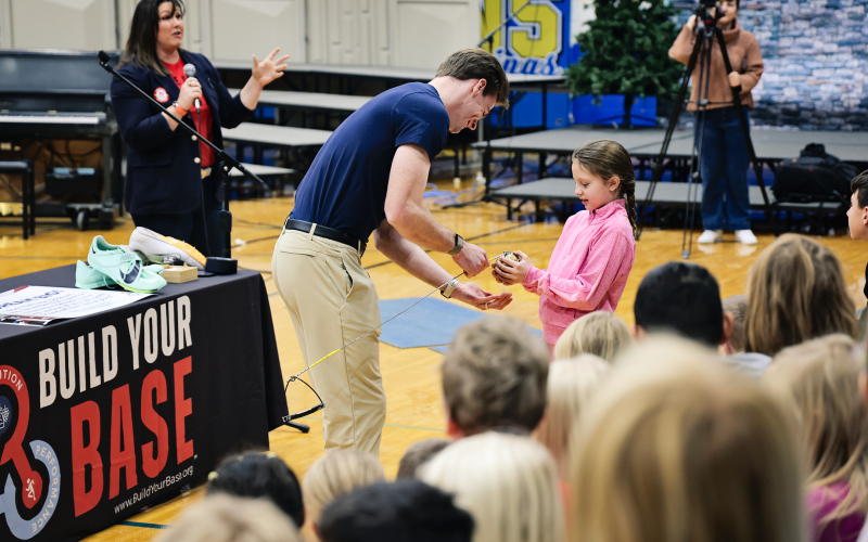 U.S. Olympic pole vaulter Chris Nilsen lets elementary student Mary Tanke try the weight of teammate DeAnna Price’s 8.8-pound hammer during the athletes’ visit to Wessington Springs School on Dec. 4.