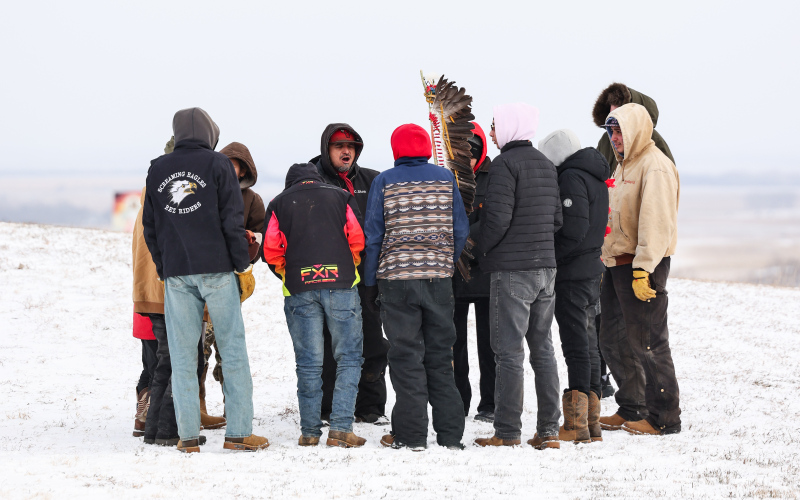 Participants in the Makatoh Reconciliation and Healing Horse Ride pray in the American Legion parking lot after arriving in Wessington Springs. (KRISTI HINE / TRUE DAKOTAN)