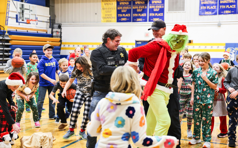 The Grinch is led from the Wessington Springs Elementary School gymnasium by Jerauld County Sheriff Jason Weber and Deputy Mike Krueger on Friday, Dec. 19, as students erupt in cheers following his apprehension. (KRISTI HINE / TRUE DAKOTAN)